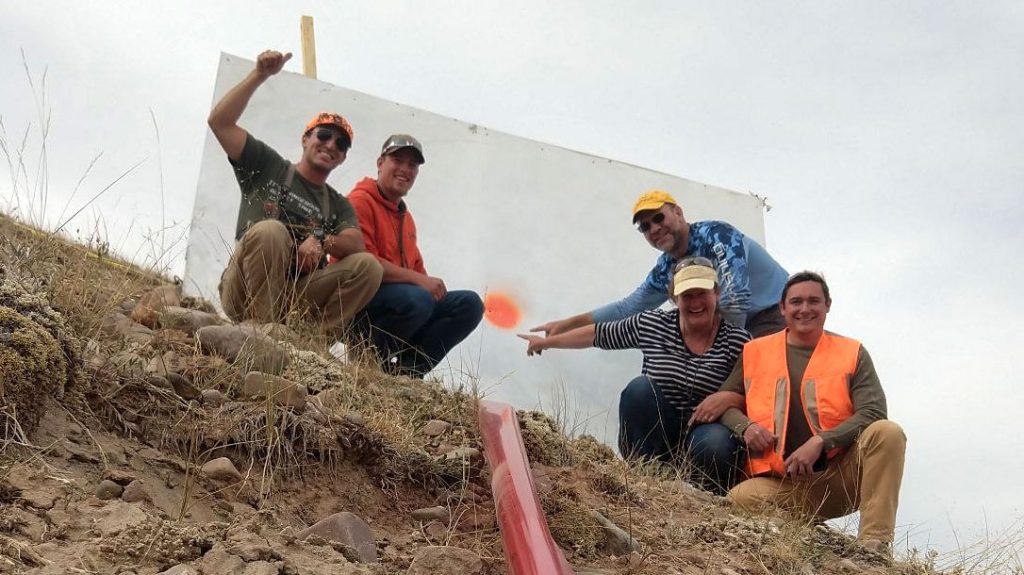 The spotting team takes a photo with the target after setting the world record for extreme long range shot.