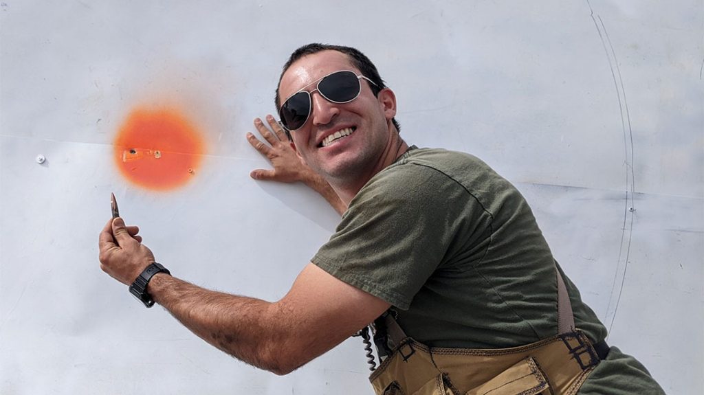 A spotter poses with the bullet in front of the bullseye.