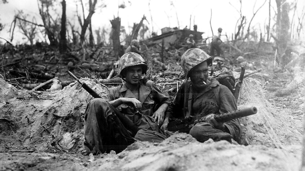 Marine Pfc. Douglas Lightheart (right) cradles his .30 caliber (7.62×63mm) M1919 Browning machine gun in his lap, while he and Pfc. Gerald Thursby Sr. take a cigarette break, during mopping up operations on Peleliu on 14 September 1944.