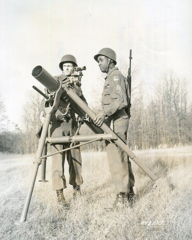 Two soldiers carry a Davy Crockett on its tripod to the firing location.