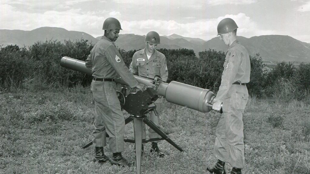 Three soldiers perform a systems inspection before loading the recoilless rifle.